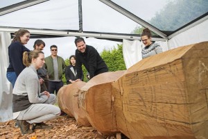 Rande Cook and his class examine the pole he's carving (Photo Services)