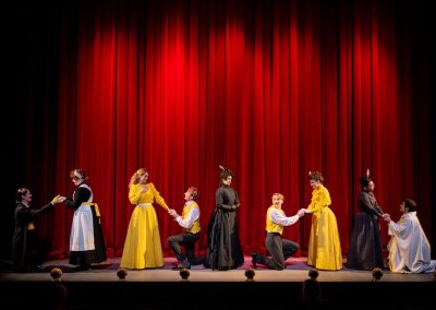 actors in black and yellow costumes in the importance of being earnest curtain call
