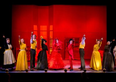 actors in red, yellow, and black costumes in the importance of being earnest curtain call